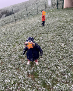 Enfants sous la neige dans le jardin de la crèche